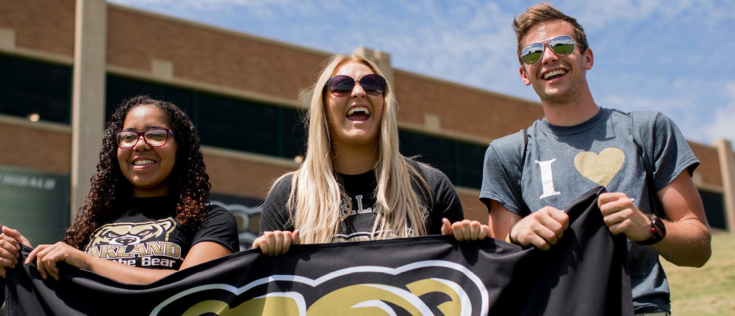 三个O U学生持有黄金的黑旗一定头吉祥物。