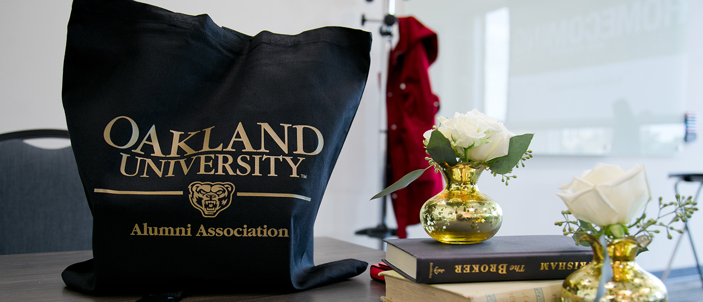 万博ManBetX登录奥克兰大学校友会的书包放在桌子上，旁边是书和花瓶里的花。