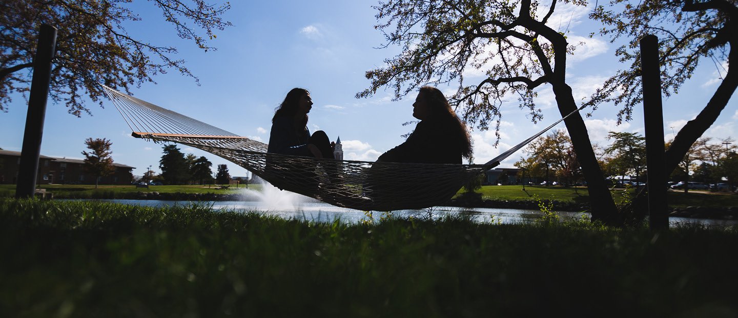 两人坐着,面对彼此,在吊床上湖和喷泉。