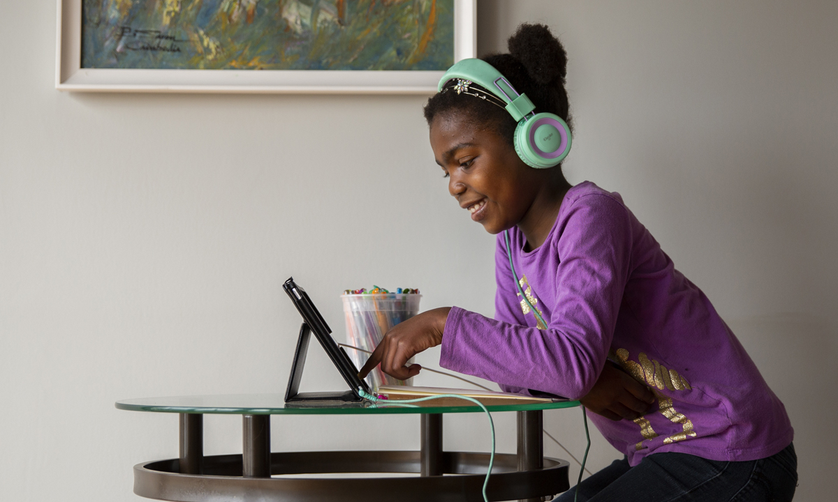 图像的一个小孩戴着耳机坐在电脑前和微笑