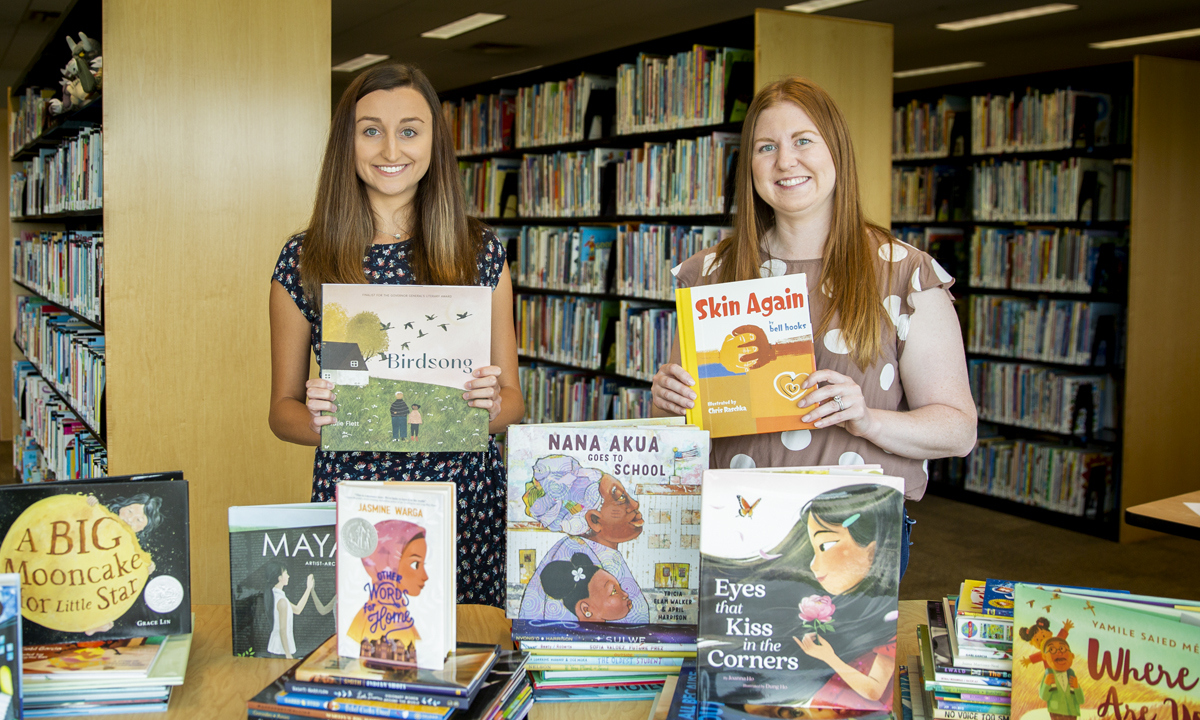 两个大学生的形象站在成堆的书在图书馆