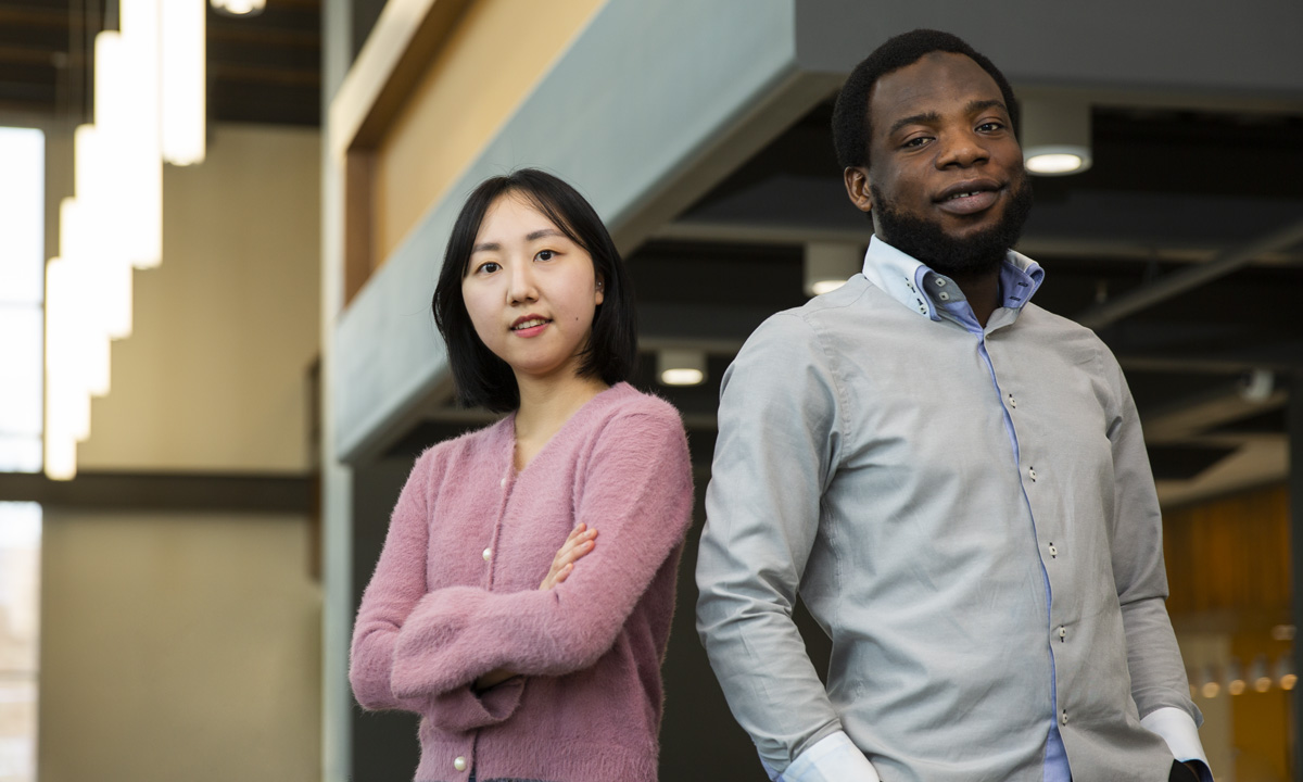 照片中，一名大学年龄的女子站在一名大学年龄的男子旁边，两人都微笑着看着镜头。