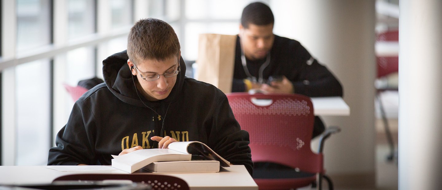 两个学生戴着耳机,张开的书坐在一桌