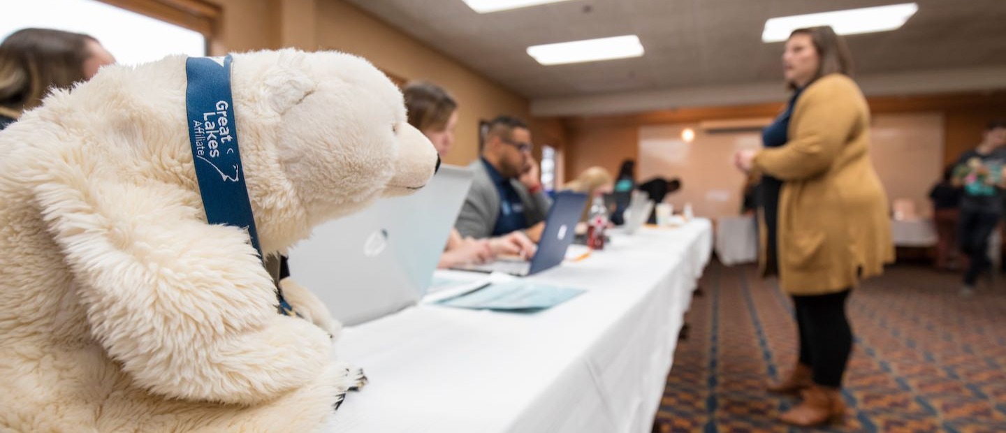 北极熊毛绒玩具在长桌上的照片，学生们用电脑和学生们交谈
