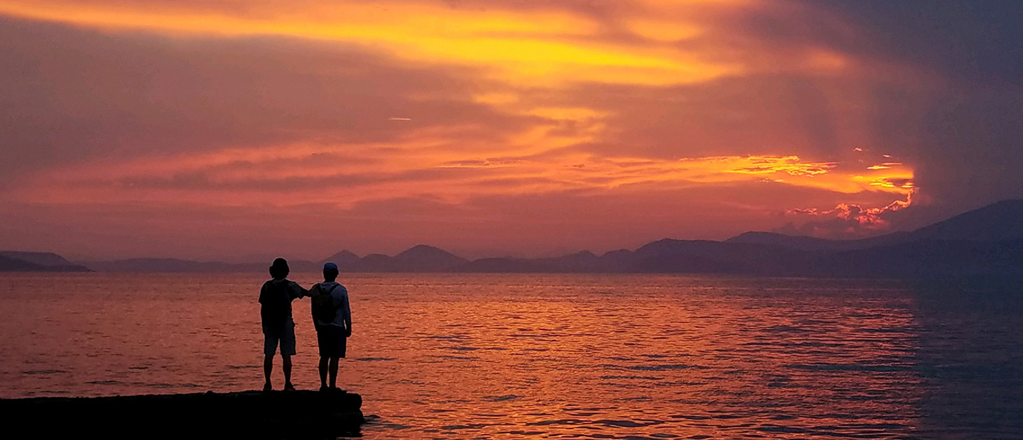 两个人面对着一大片水面上的日落