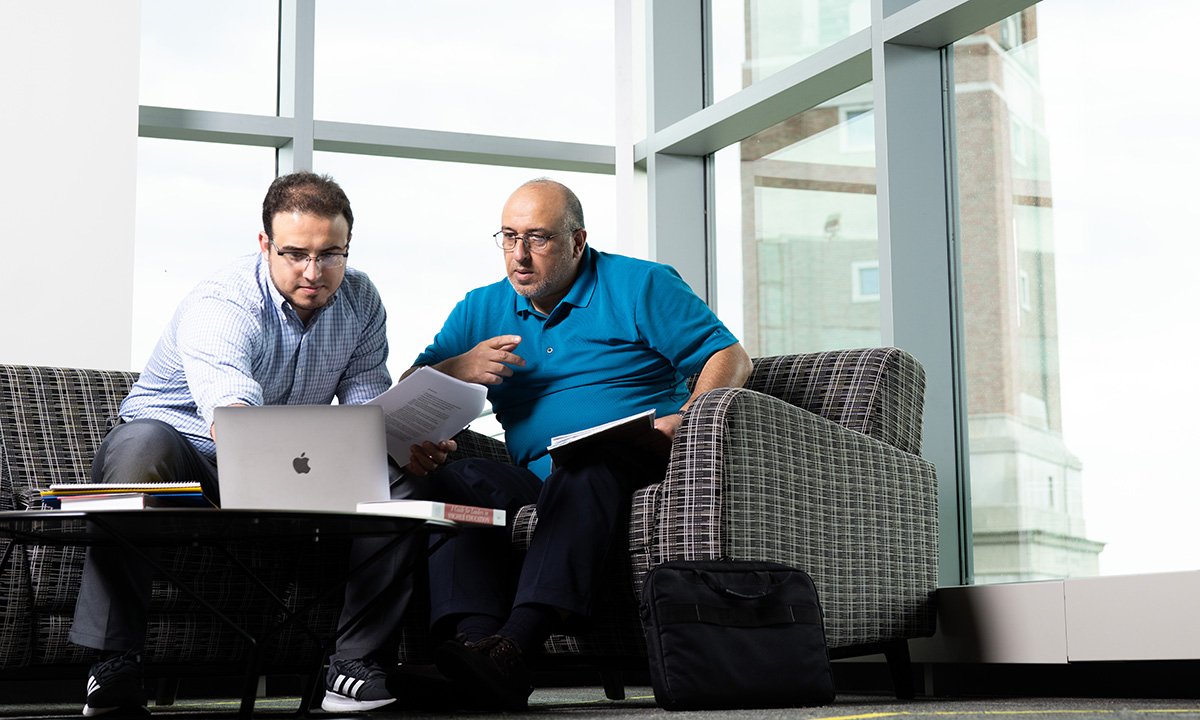 两个男人坐着一台笔记本电脑