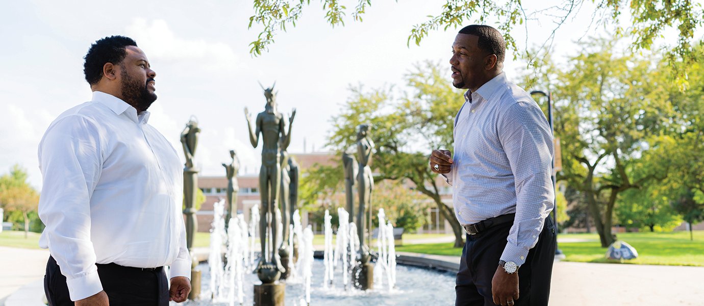 两名男子站在奥克兰大学校园的喷泉前。万博ManBetX登录