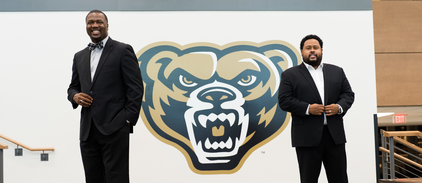 两个男人站在棕熊的标志前