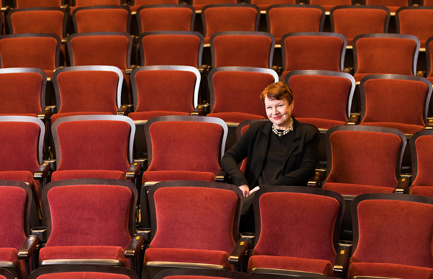 一个女人坐在剧院,周围是红色的席位