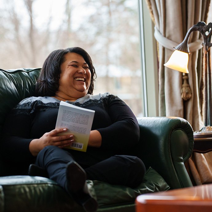 一个女人坐在椅子上,手里拿着一本书,笑了