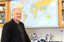 生物学教授Taras Oleksyk站在墙上的地图前。