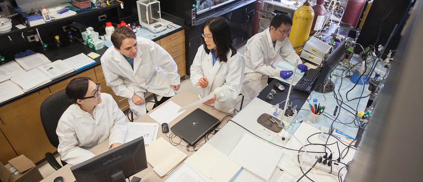 人们穿着白大褂在实验室工作。