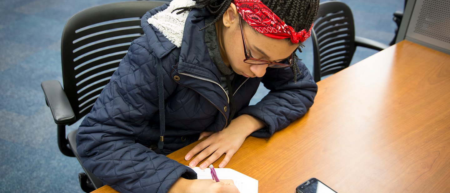 一个学生坐在桌旁写字。