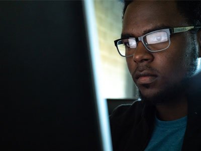 男学生在电脑工作,屏幕反射可以看到在他的眼镜。