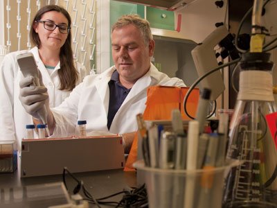 男人和女人穿着白色外套,在一个实验在一个实验室工作。