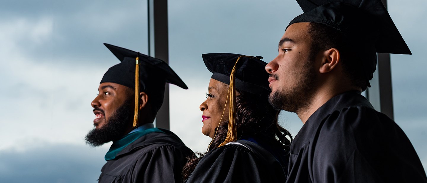 三个非裔美国人学生在他们的毕业帽和礼服。