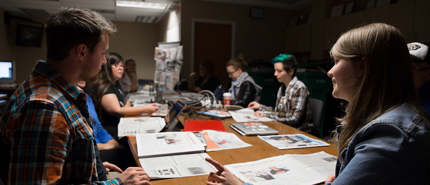 群学生围坐在一张桌子覆盖着打开报纸
