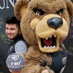 Ernesto Duran-Gutierrez，拿着第一代奥克兰大学的纽扣，与棕熊吉祥物合影。万博ManBetX登录