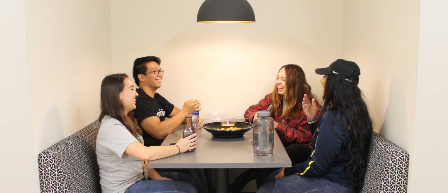 四名学生坐在一桌食物与饮料和弓在中间