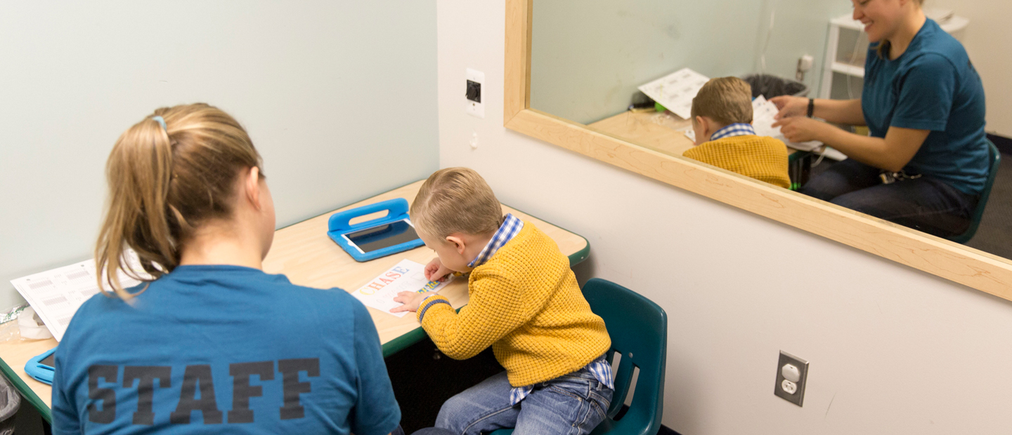 工作人员和一个小男孩坐在一个表在一个诊所。
