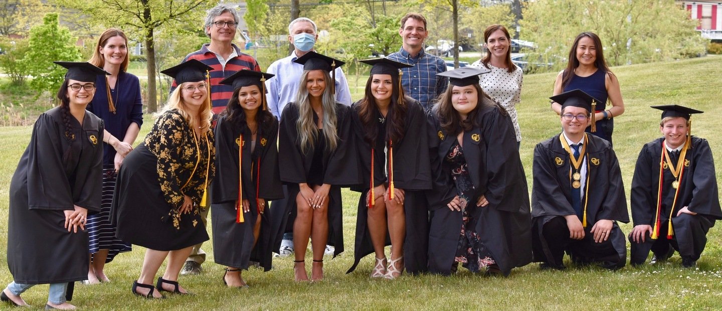 一群学生毕业帽和礼服的照片,和一行人背后便衣。