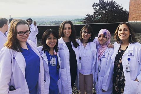 穿着白色实验服的六名女子站在屋顶