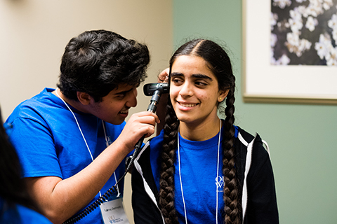 学生使用医疗器械检查另一个学生在多样性与包含项目的耳朵