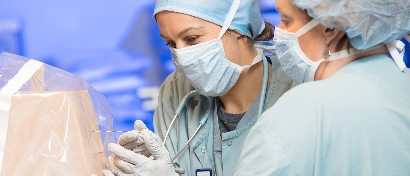 两个女人在外科礼服和面具戳一个对象在一个塑料盖