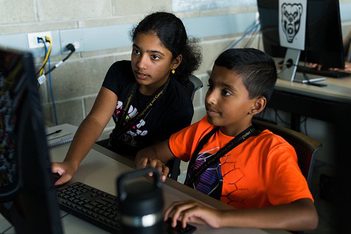 一个男孩和一个女孩看着电脑显示器