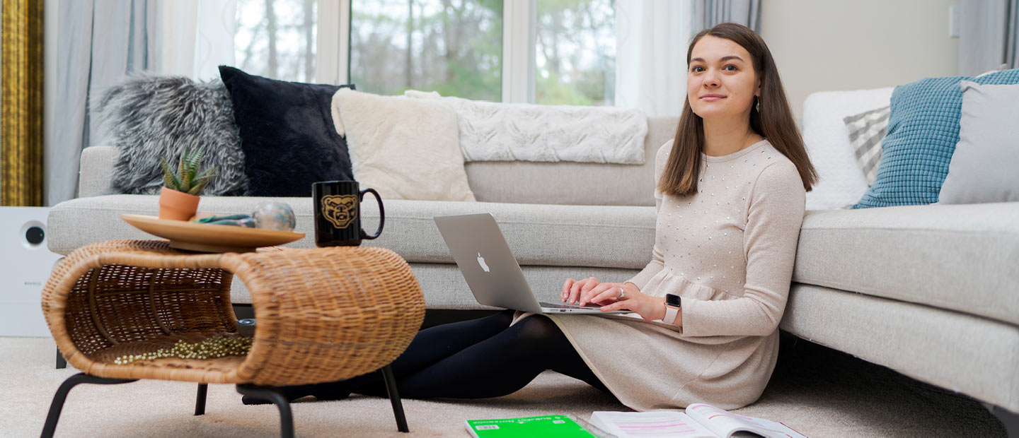 一个女人坐在客厅地板上用笔记本电脑工作