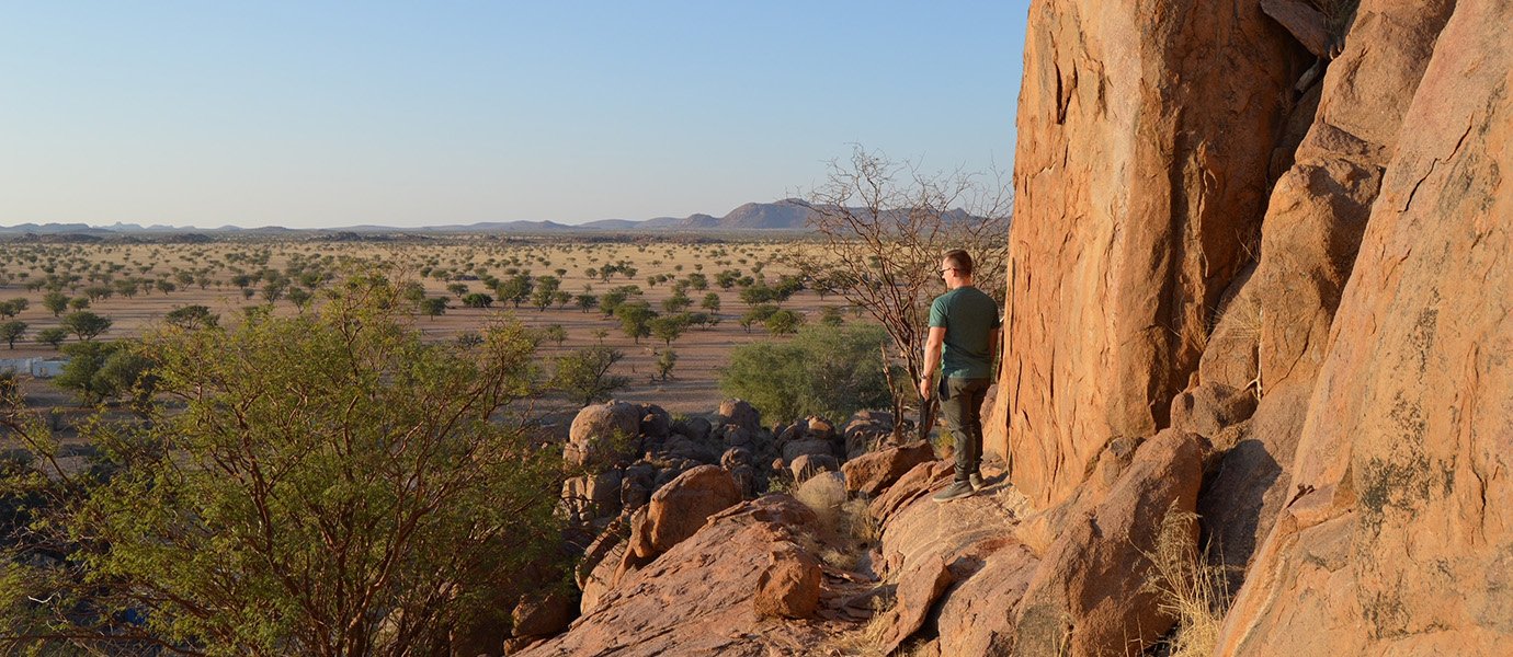 一个人站在悬崖上俯瞰沙漠的远景