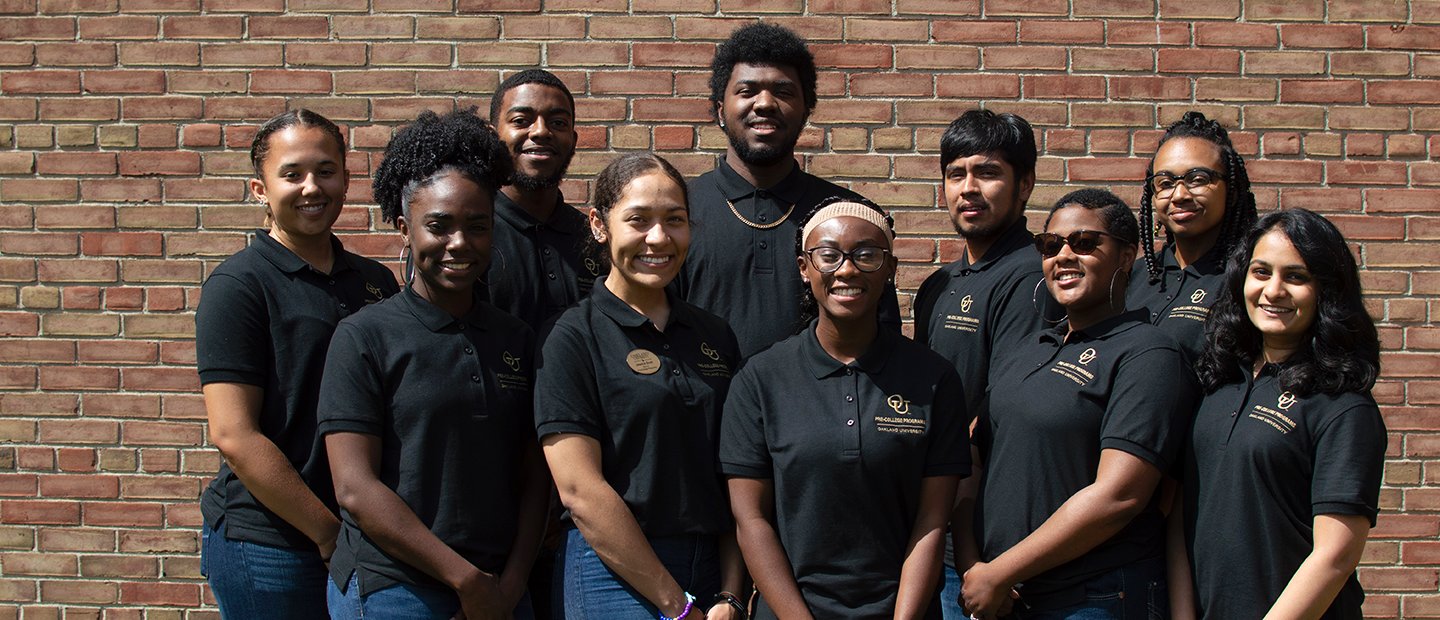 奥克兰大学的一群学生员万博ManBetX登录工穿黑色衬衫,面前的一堵砖墙。