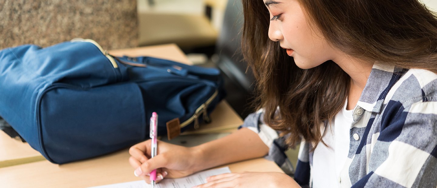 一个女学生坐在桌子前填写表格。