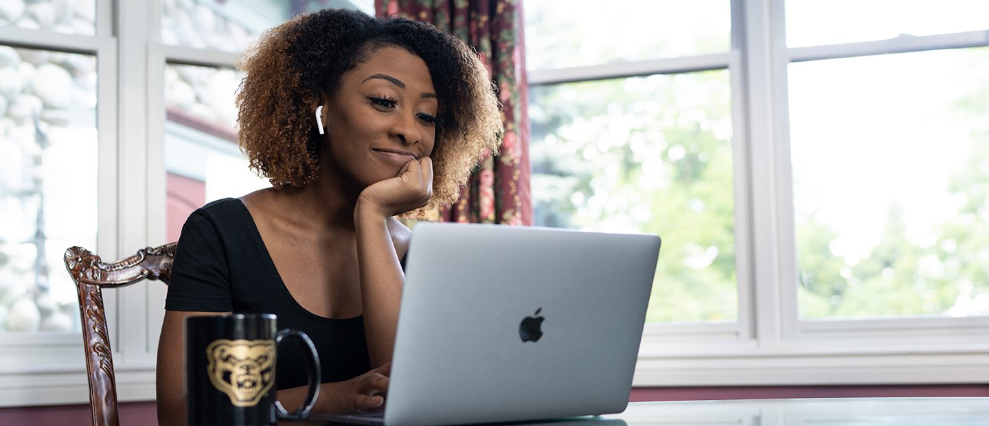 一个女学生以开放的笔记本电脑坐在一张桌子和一个咖啡杯黄金奥克兰大学马克·贝尔的形象。万博ManBetX登录