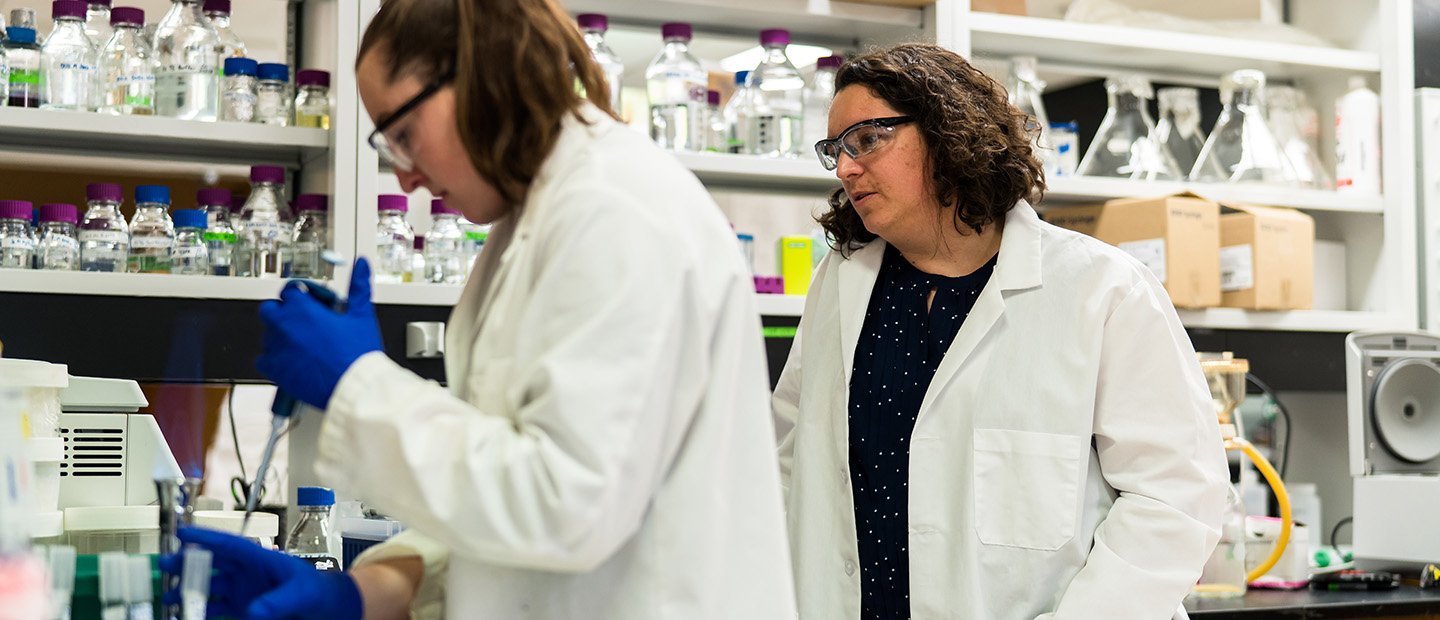 实验室里的两个女人拿着玻璃瓶里的化学药品。