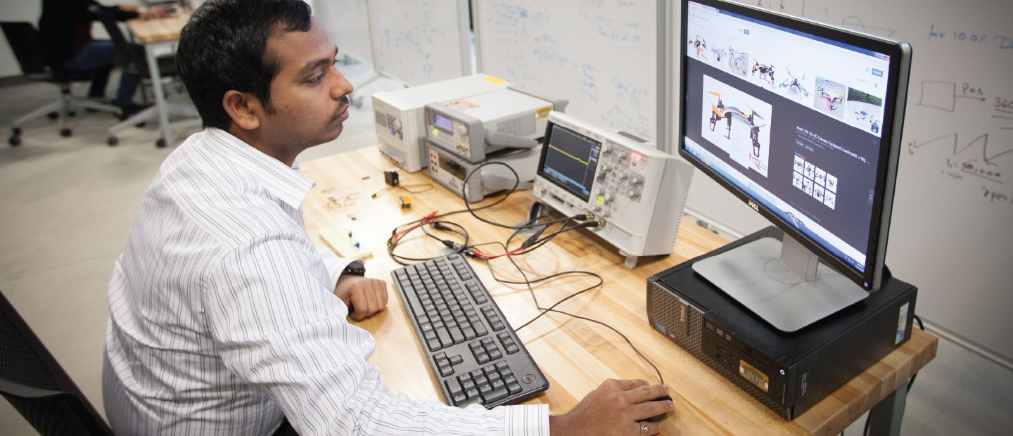 一名男子坐在电脑前，屏幕上显示着机器人的图像