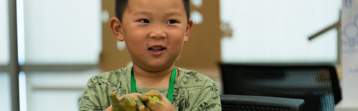 一张画着一个孩子的图片，他的手上沾满了绿色的东西，正在微笑