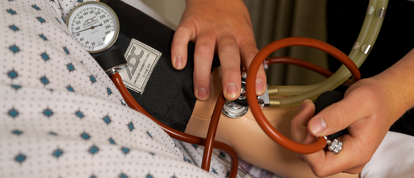 一个人在医用假人身上测试血压的图像