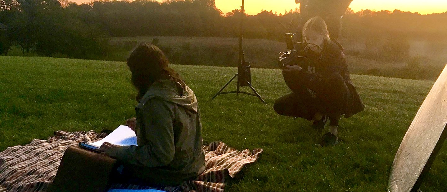 一个年轻女人拍照的人坐在外面一条毯子,看书。