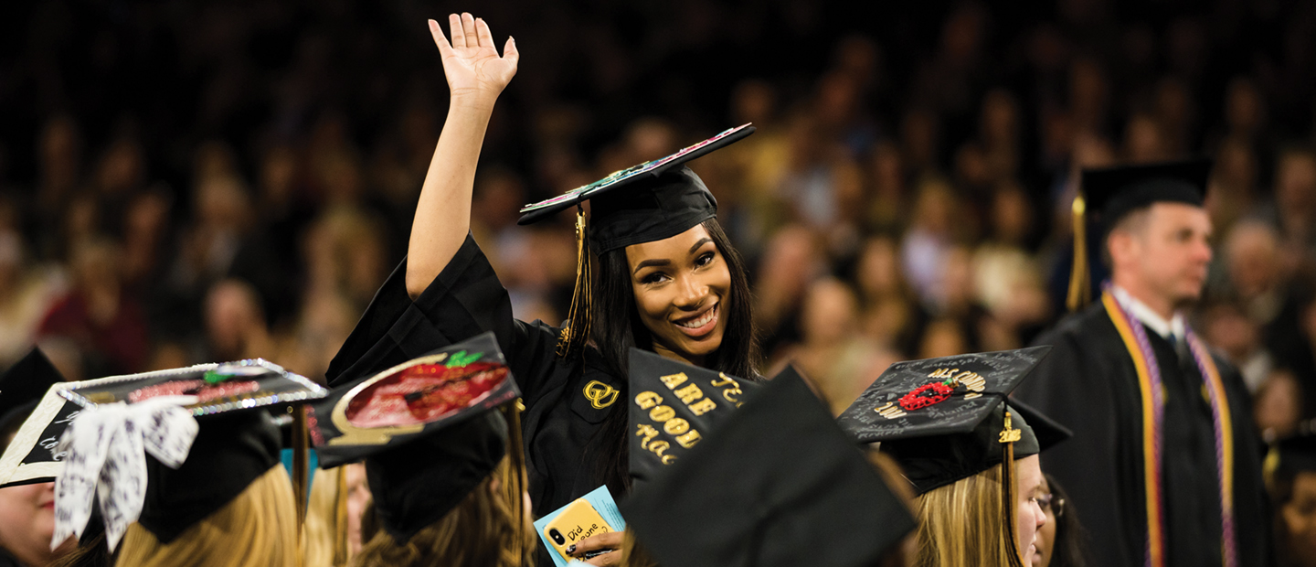 横幅上有一个穿着毕业装的女人微笑着挥手，周围是其他毕业生。