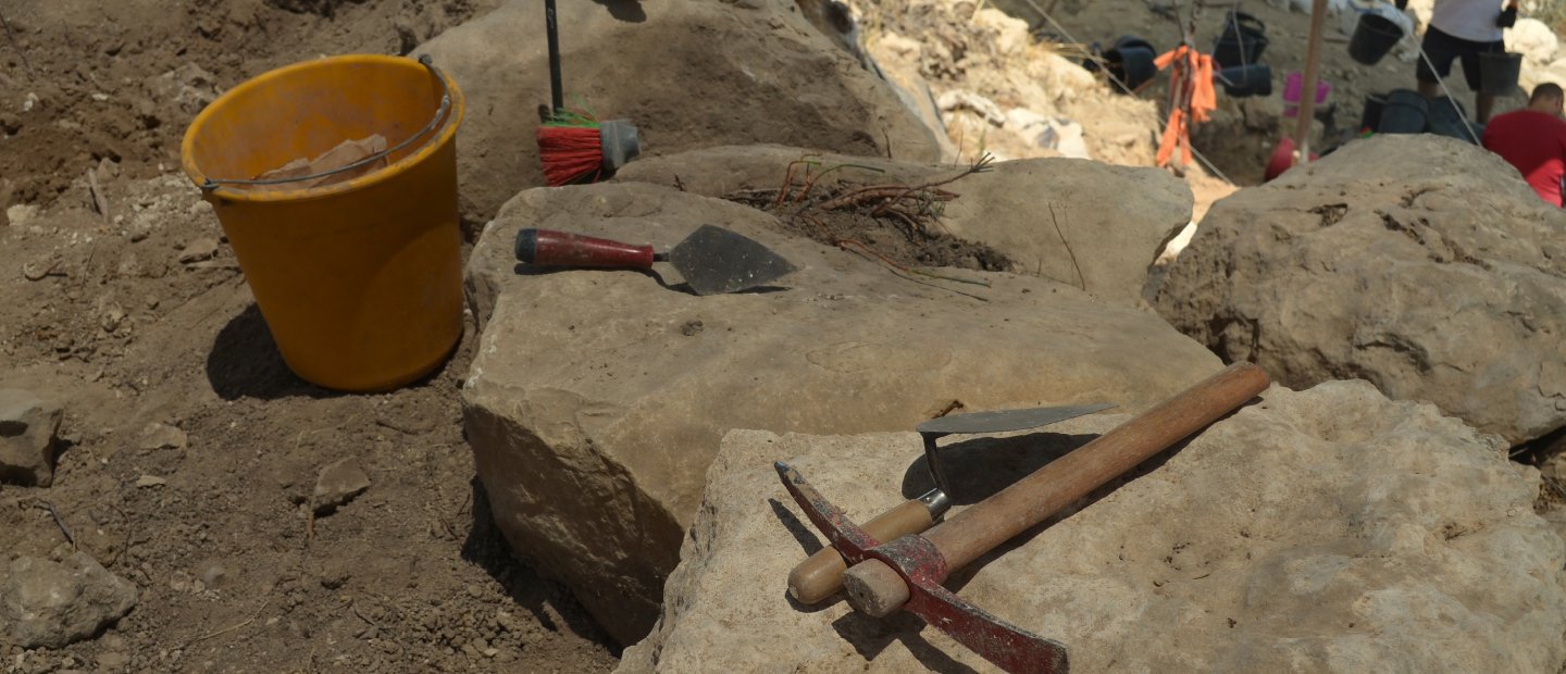 在考古挖掘现场工具坐在石头上。