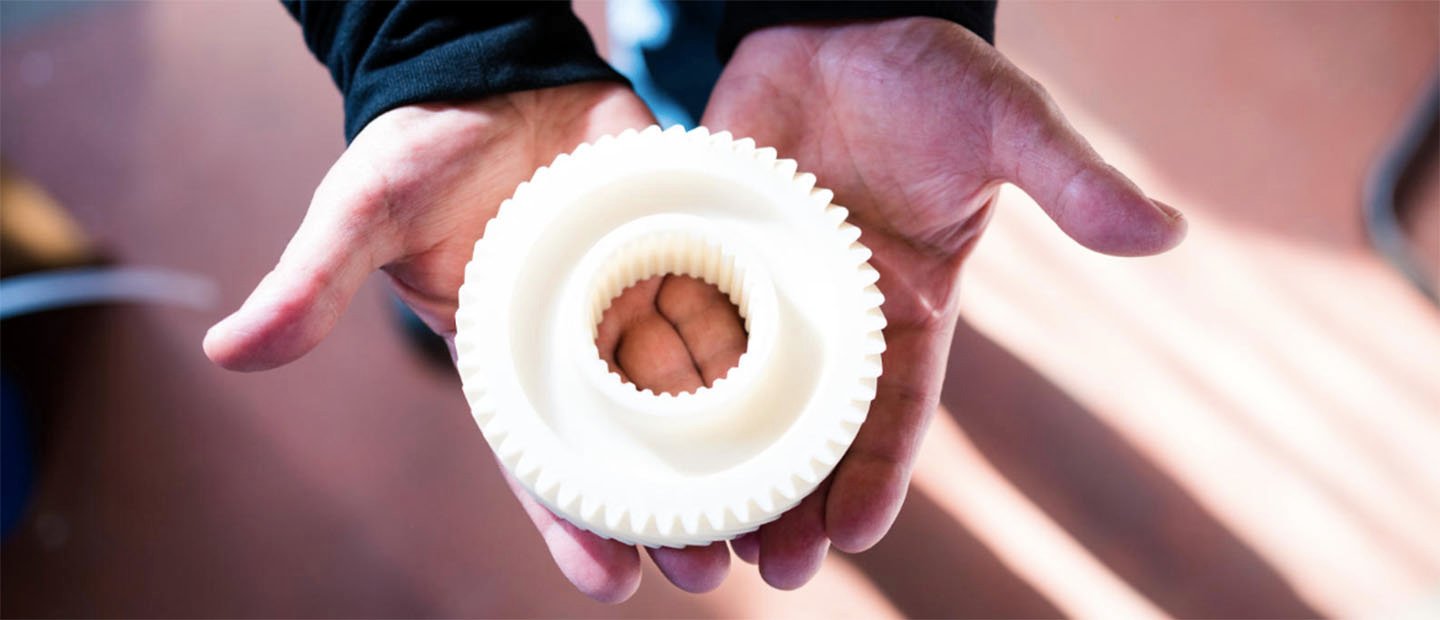 两只手拿着一个圆形的白色甜甜圈形状的物体，边缘有齿轮状的牙齿。